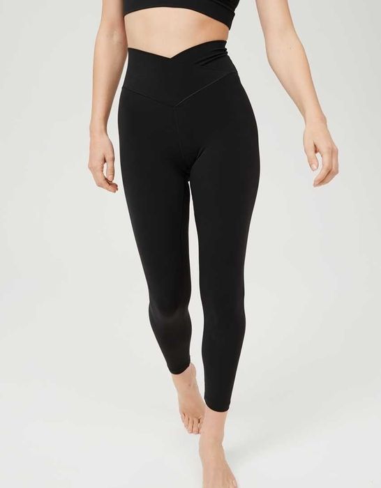 A model showcases a pair of black leggings featuring a unique V-shaped waist design.