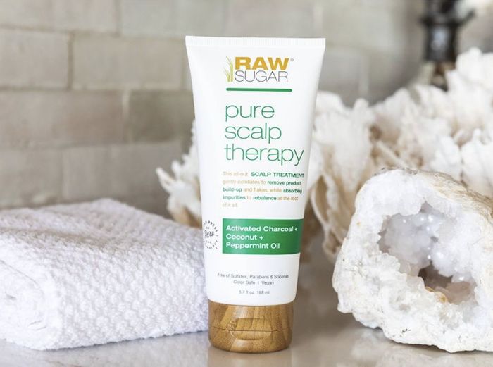 A tube of hair treatment, a white towel, and a loofah sponge.