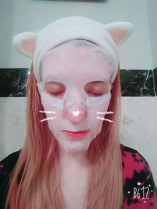 a reviewer wearing the headband to hold back her hair while applying a sheet mask