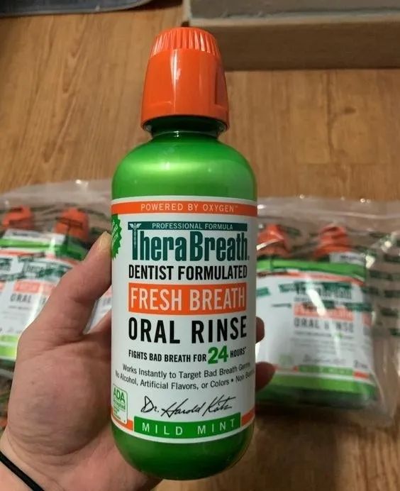 A hand holding the large bottle of oral rinse