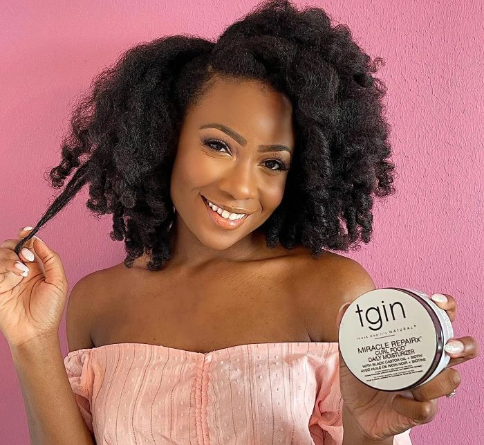 Model showcasing healthy curls while holding the product