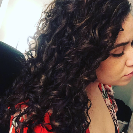 A reviewer displaying their long brown curls perfectly intact after using the sleep beanie