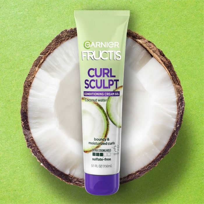 A tube of cream-gel next to a sliced coconut.