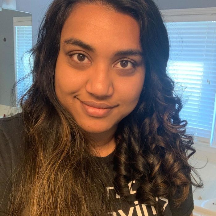 A reviewer displaying one side of their hair curled and the other side natural, captured mid-curling process