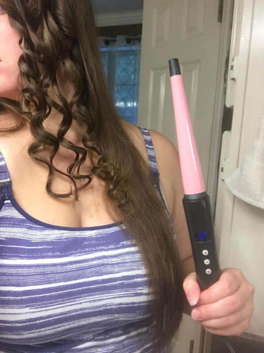A reviewer in the process of curling their hair with the wand