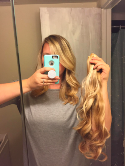 A reviewer holding the hair extensions next to their head, highlighting their short hair