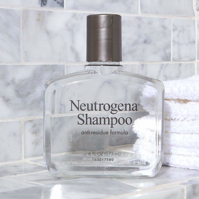the clear shampoo bottle resting on a shower ledge