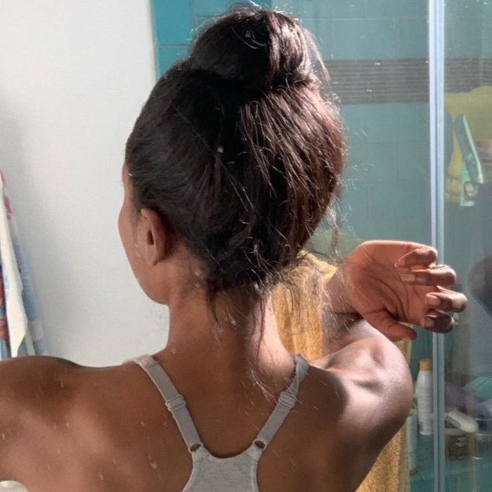 A before photo of a reviewer with their hair tied up in a bun and flyaways visible at the neck