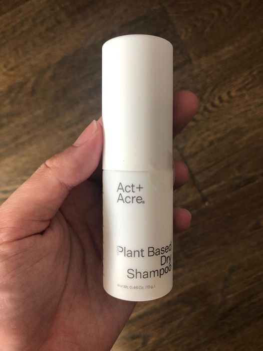 A reviewer holding the bottle of dry shampoo