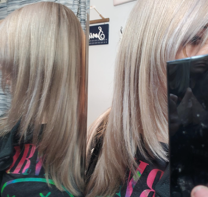 A person with a layered, straight hairstyle after a salon visit, wearing a vibrant graphic T-shirt