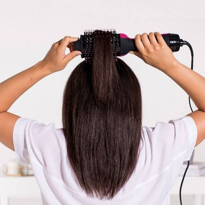 A person styling their hair with a hairstyling tool.