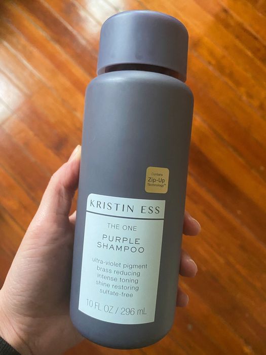 Britt holding up a bottle of the purple shampoo