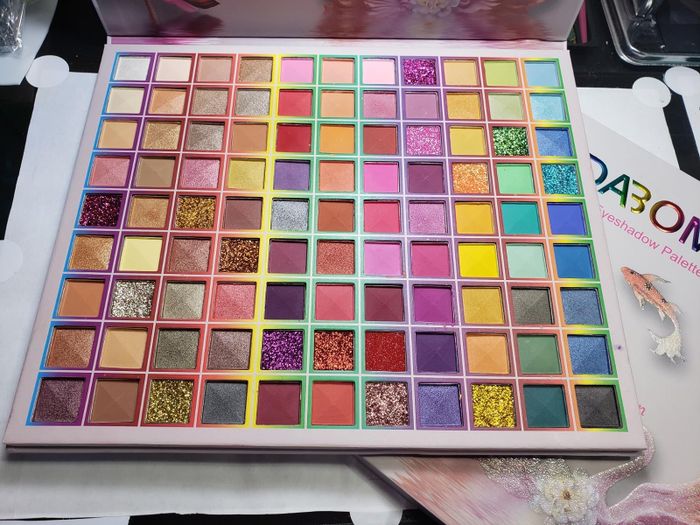 A large eyeshadow palette featuring a diverse range of shades and finishes, including matte, shimmer, and glitter textures.