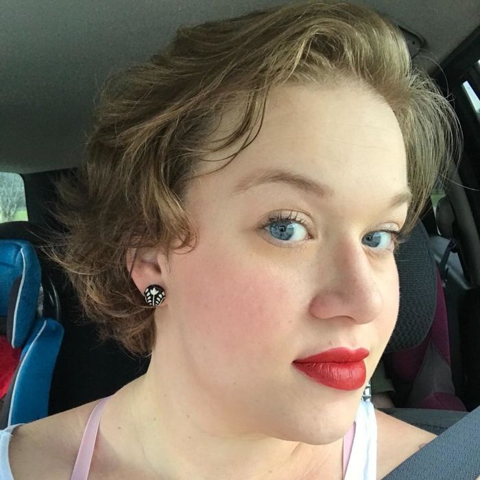 A reviewer showcasing a bold red shade of the lipstick