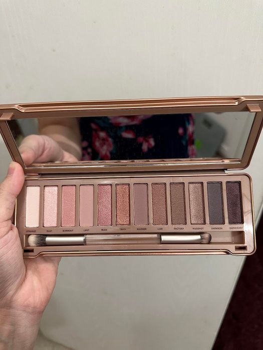 A reviewer holding an eyeshadow palette featuring 12 different shades