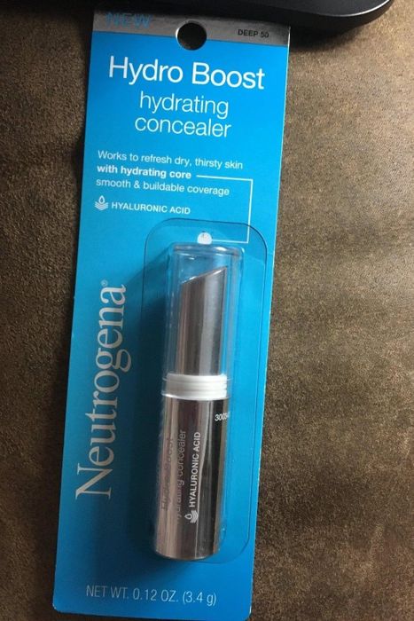 A reviewer displaying the concealer in its original packaging
