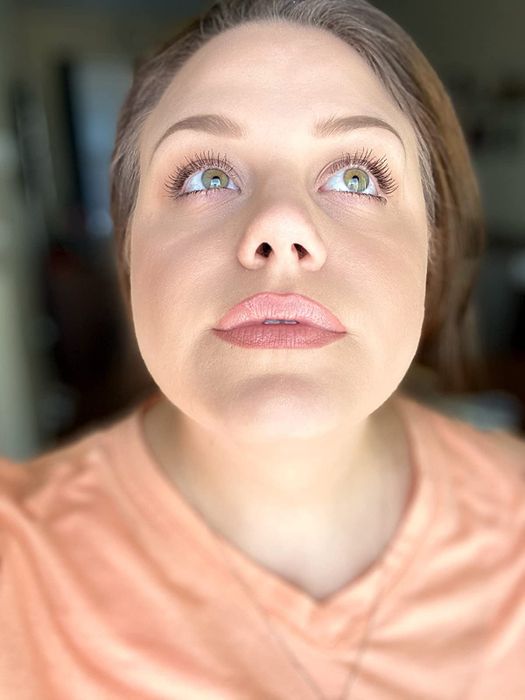 a reviewer photo of them displaying the lip product applied to their lips