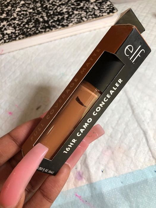 A reviewer holding the concealer tube for display