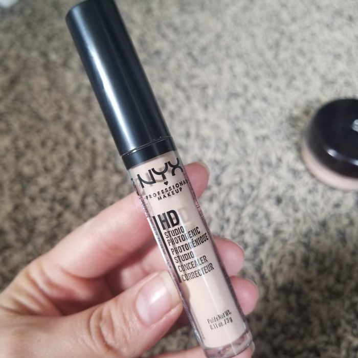 A reviewer holding the concealer tube for demonstration
