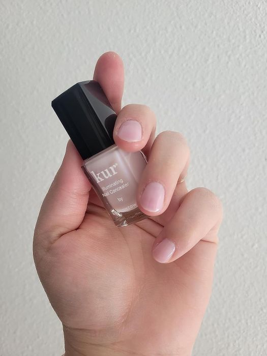 A reviewer holding the concealer product