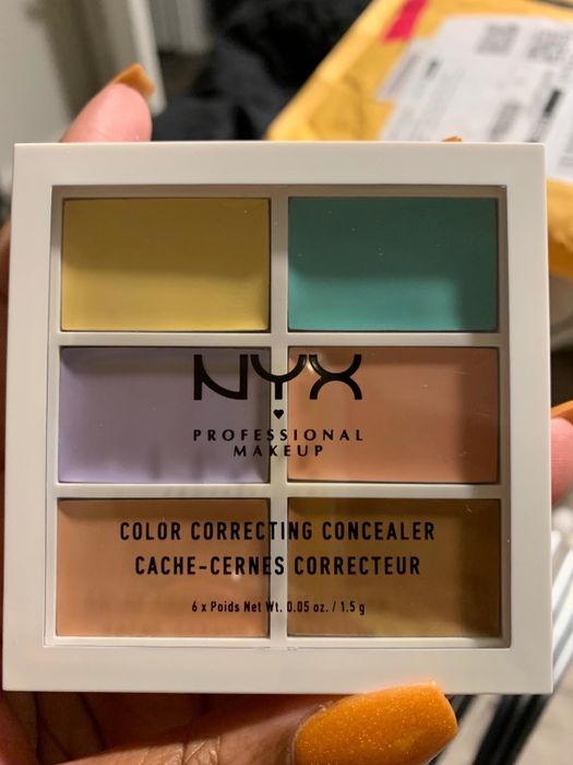 A reviewer holding the concealer palette for demonstration