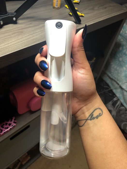 A reviewer proudly displaying their spray bottle.