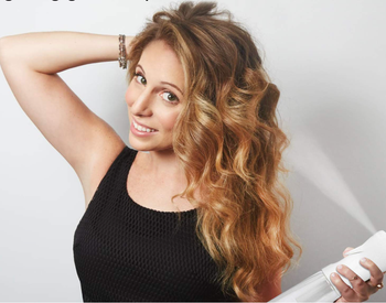 A model using the mister to refresh their long, flowing hair.