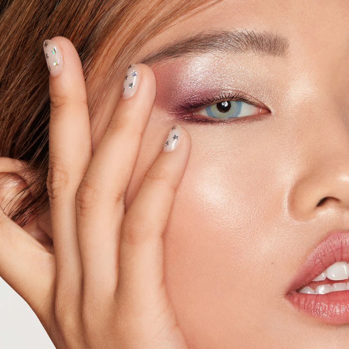 a model applying a shimmery pink eyeshadow