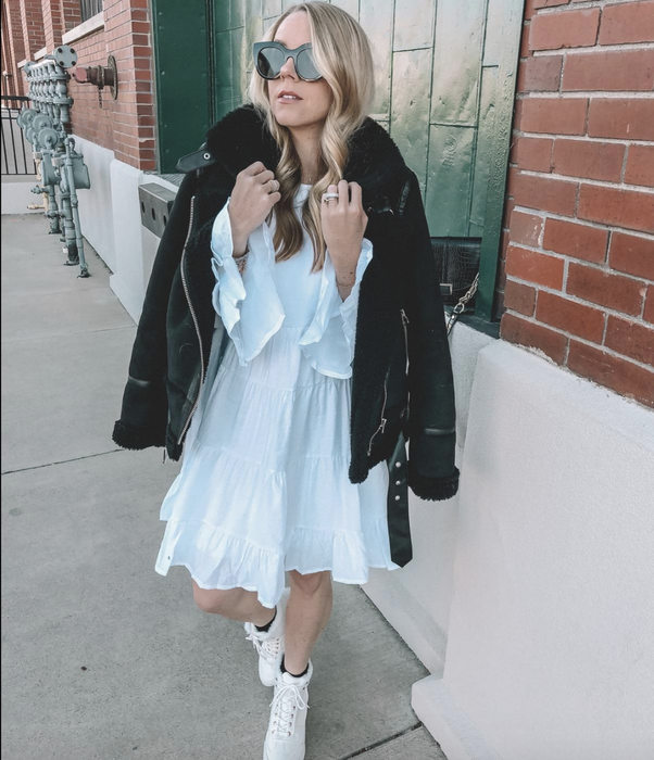 reviewer wearing a white dress paired with a black jacket