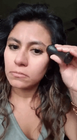 A reviewer using the Revlon oil-absorbing volcanic face roller to achieve a matte finish on their face.