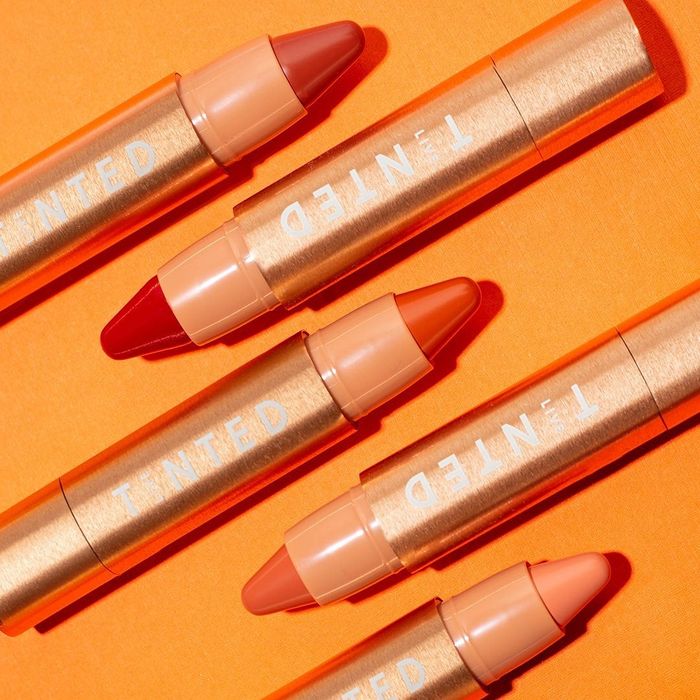 five tubes of the Huestick Corrector in shades ranging from orange to red to pink