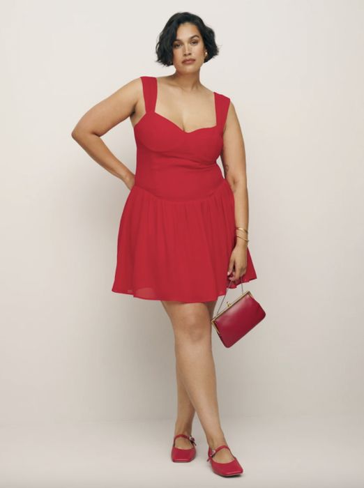 model confidently posing in a sleeveless red dress, complemented by matching shoes and a handbag