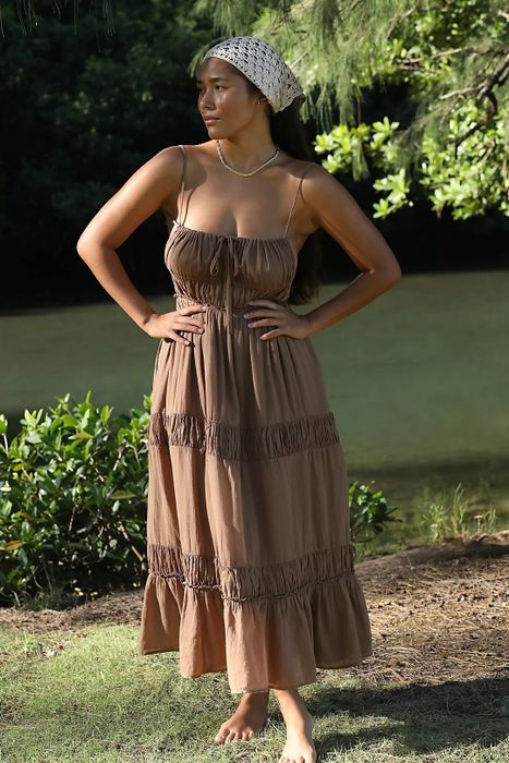 model in a tiered, sleeveless dress standing outdoors with hands on hips