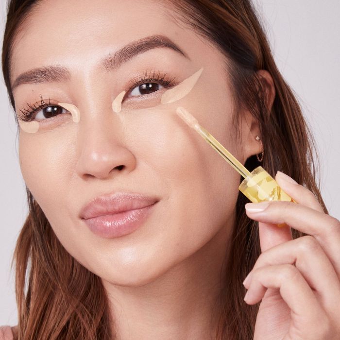 a model applying the concealer to their under-eye area