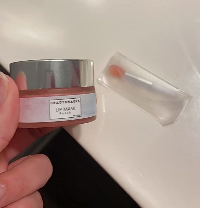 Reviewer holding the lip mask next to its applicator