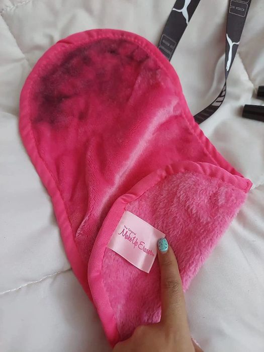 The reviewer holding the pink makeup eraser, which has makeup residue on it