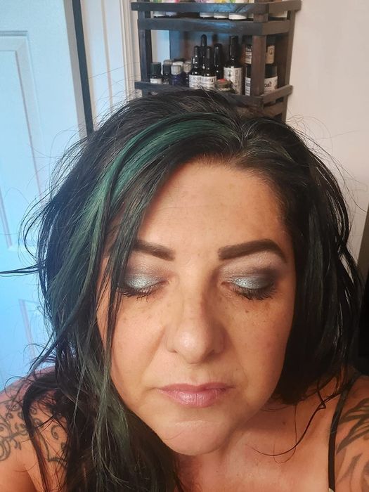 a reviewer photo capturing a downward glance to highlight the greenish metallic eyeshadow applied to their eyelids