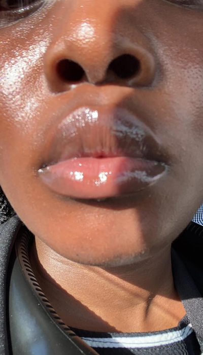 A close-up of a reviewer’s glossy lips and part of their face, dressed in a striped shirt.