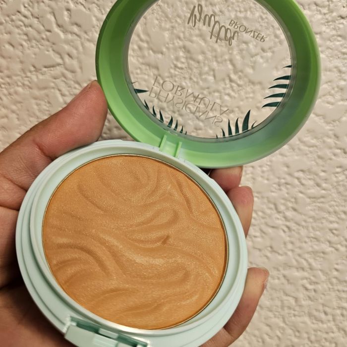 A hand holding an open compact case of Physicians Formula Butter Bronzer