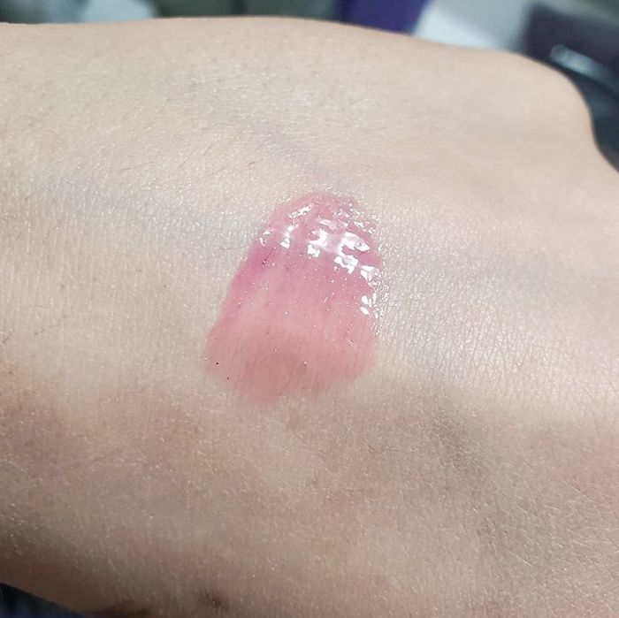 A reviewer showcasing the product with a swatch on hand.