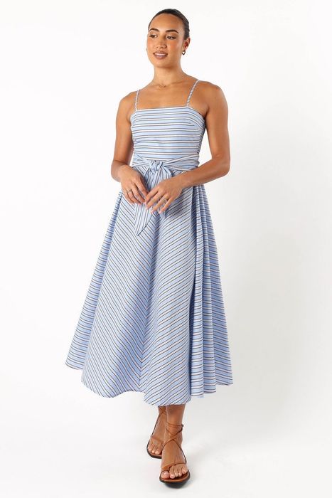 model wearing a light blue spaghetti strap flared dress with stripes and a tie belt