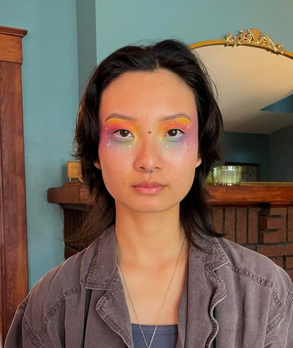 A reviewer showing off their vibrant rainbow eye makeup