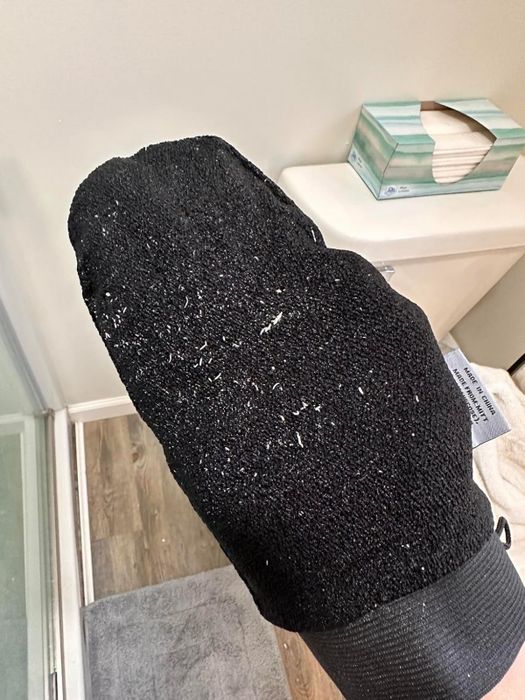 A black exfoliating glove filled with removed dead skin