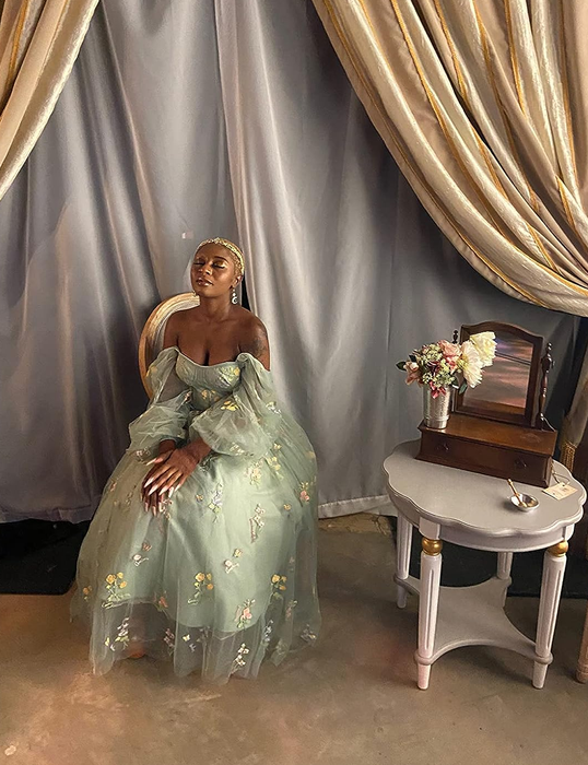 reviewer seated in an elegant off-the-shoulder tulle gown