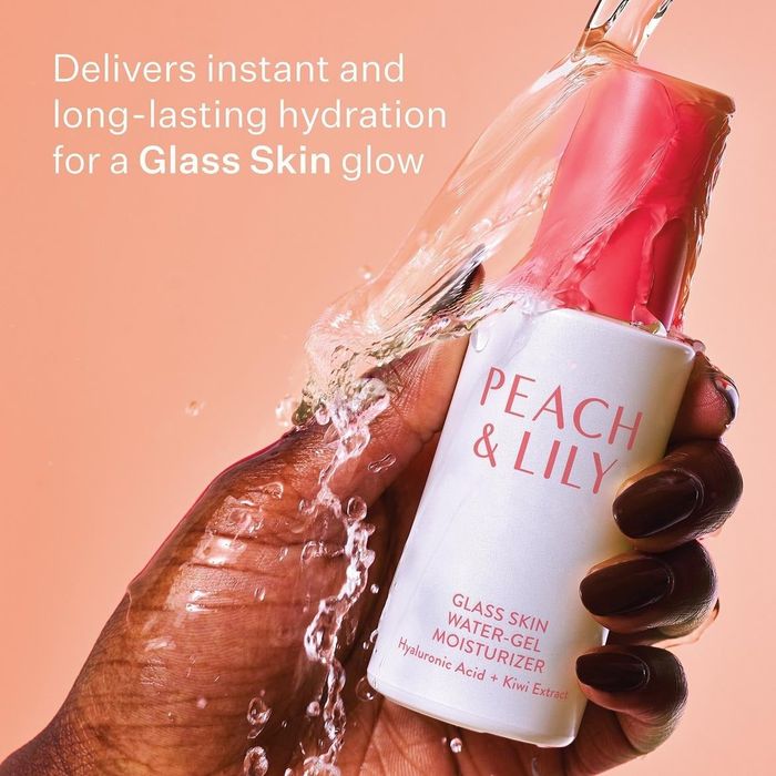 A hand holding a bottle of Peach & Lily Glass Skin Water-Gel Moisturizer, with water splashing around it. Text on the image reads: