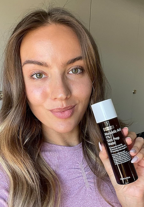 A reviewer holding the bottle, with visibly radiant skin