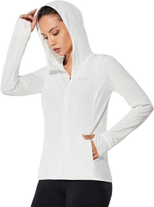 A model posing in a white jacket, one hand on the hood and the other in the pocket