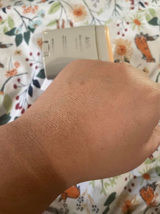 A person's hand showcasing smooth, clear skin after applying a transparent sunscreen product