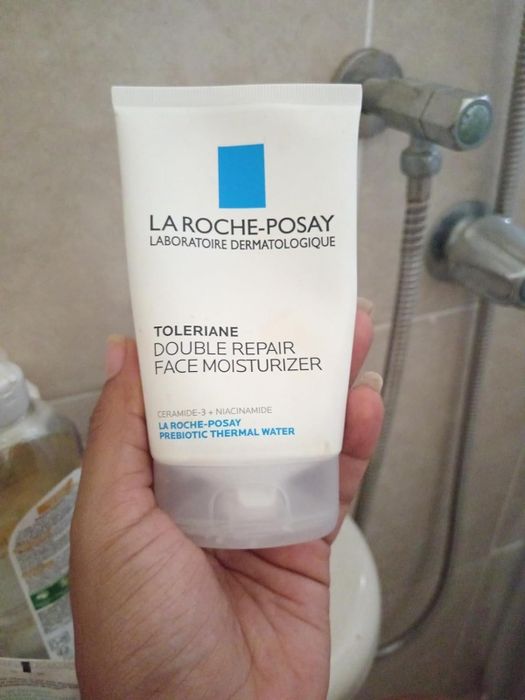 A reviewer holding a tube of La Roche-Posay Toleriane Double Repair Face Moisturizer