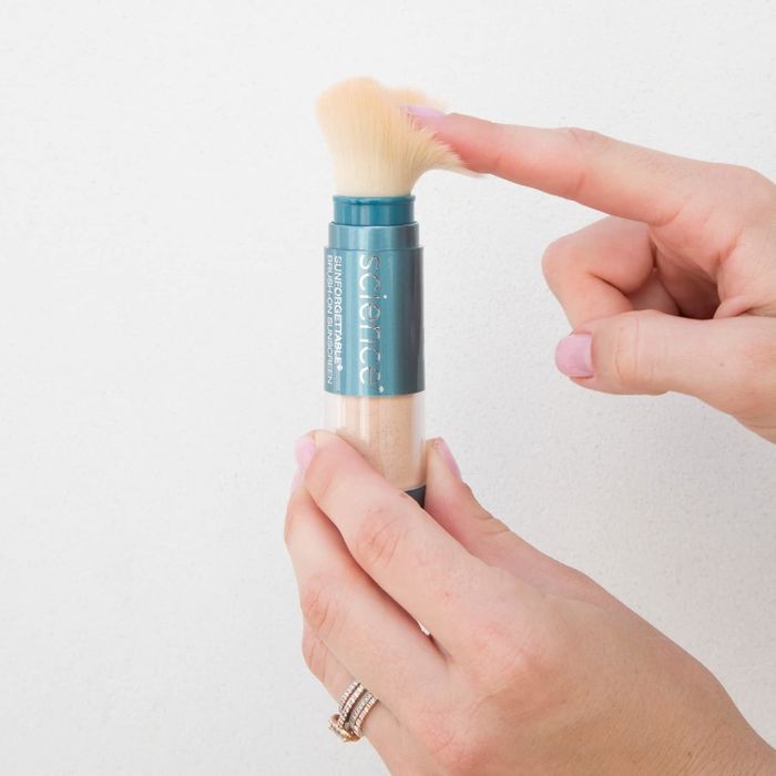 An individual holding a ColoreScience SunForgettable Mineral Sunscreen Brush